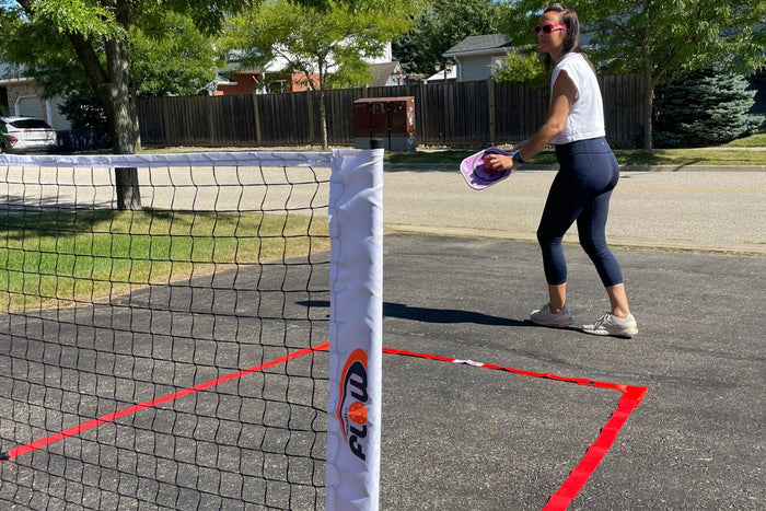 Female pickleball player serving on the mini court